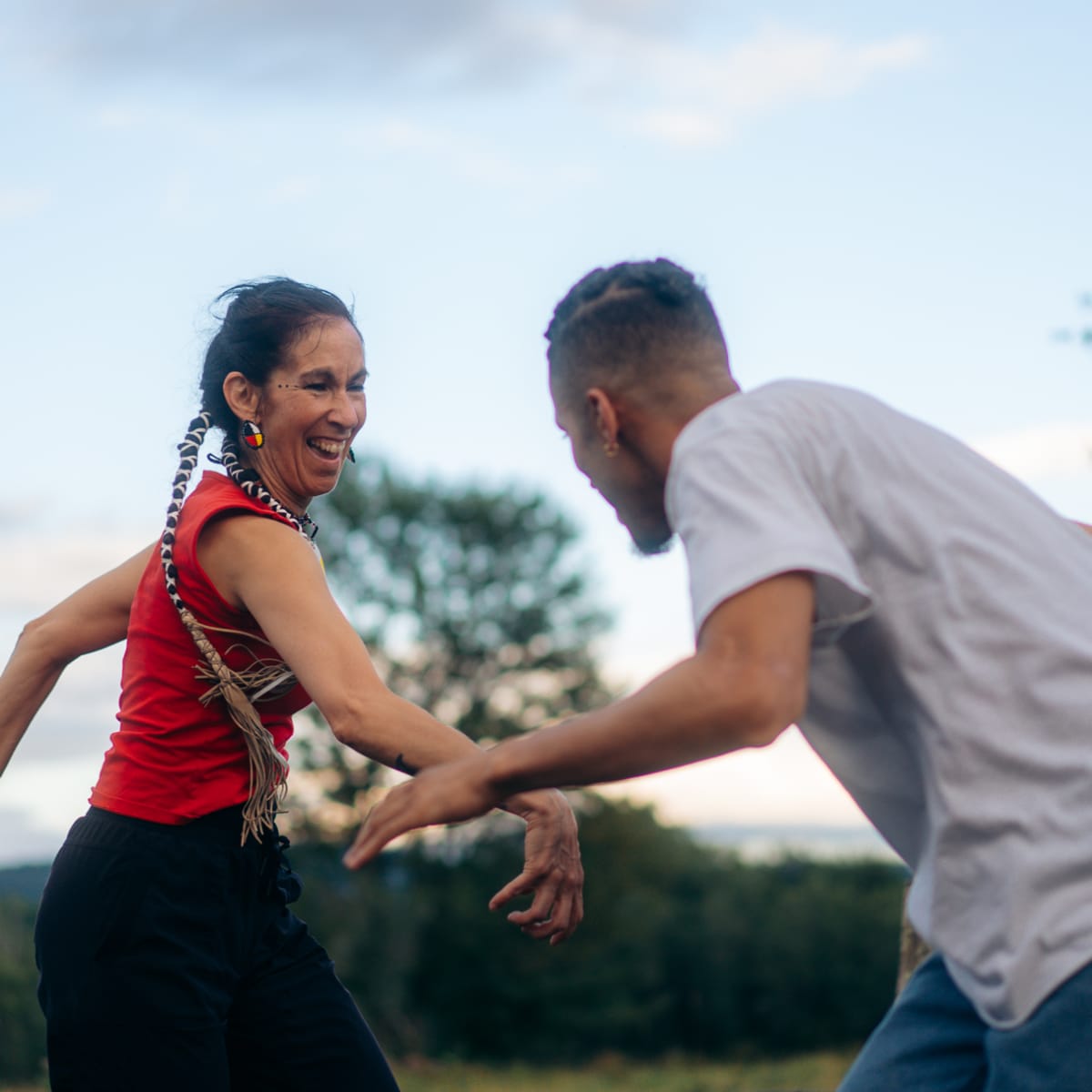 Une femme autochtone et un homme dancent en nature et s'amusent