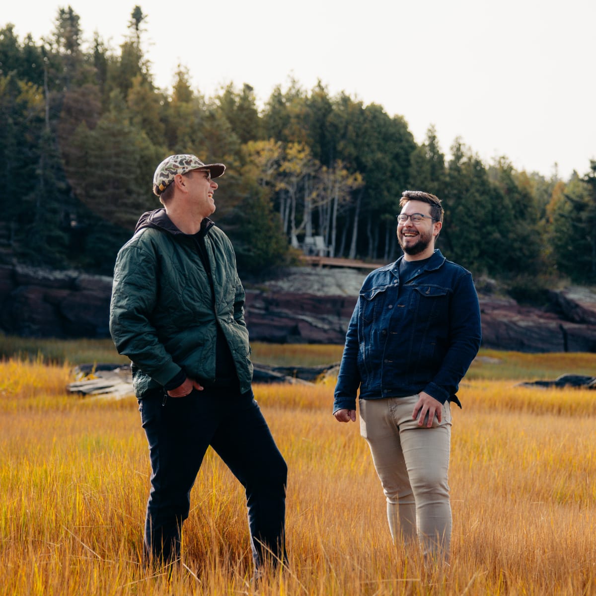 Deux hommes se sourient durant une activité en nature. 
