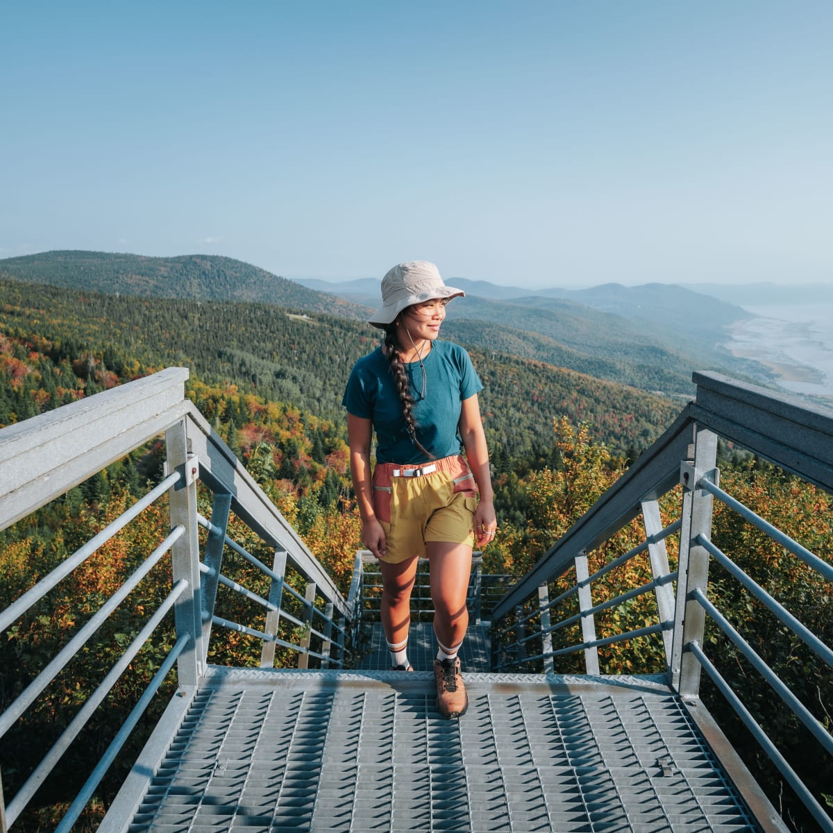 Femme en randonnée, au somment d'un escalier à flanc de montagne.