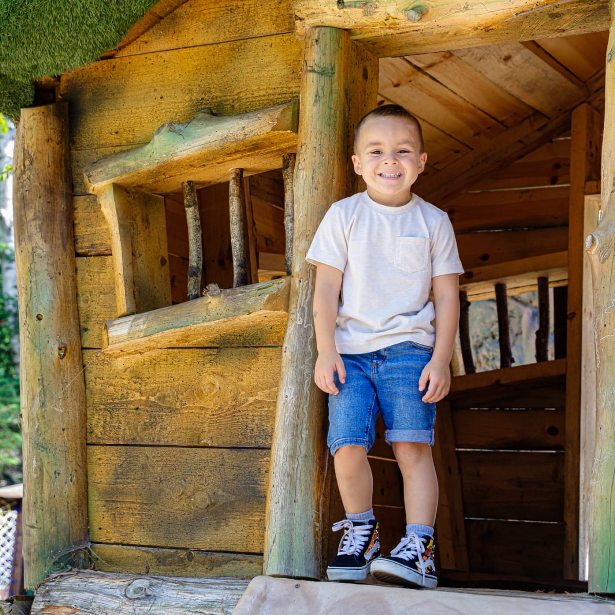 Jeune garçon devant une cabane en bois