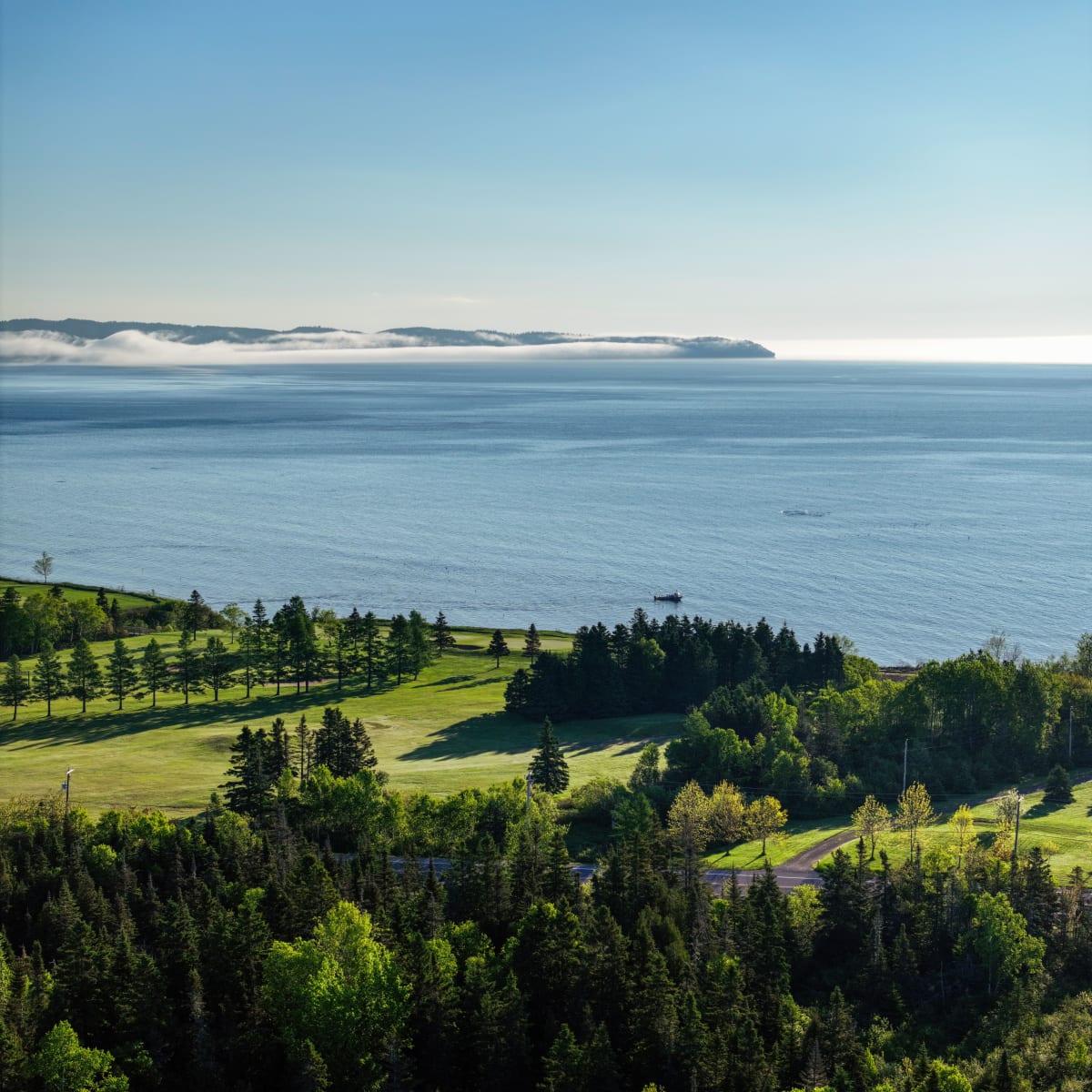 Vue aérienne d'un parcours de golf au bord de l'eau par une journée ensoleillée.