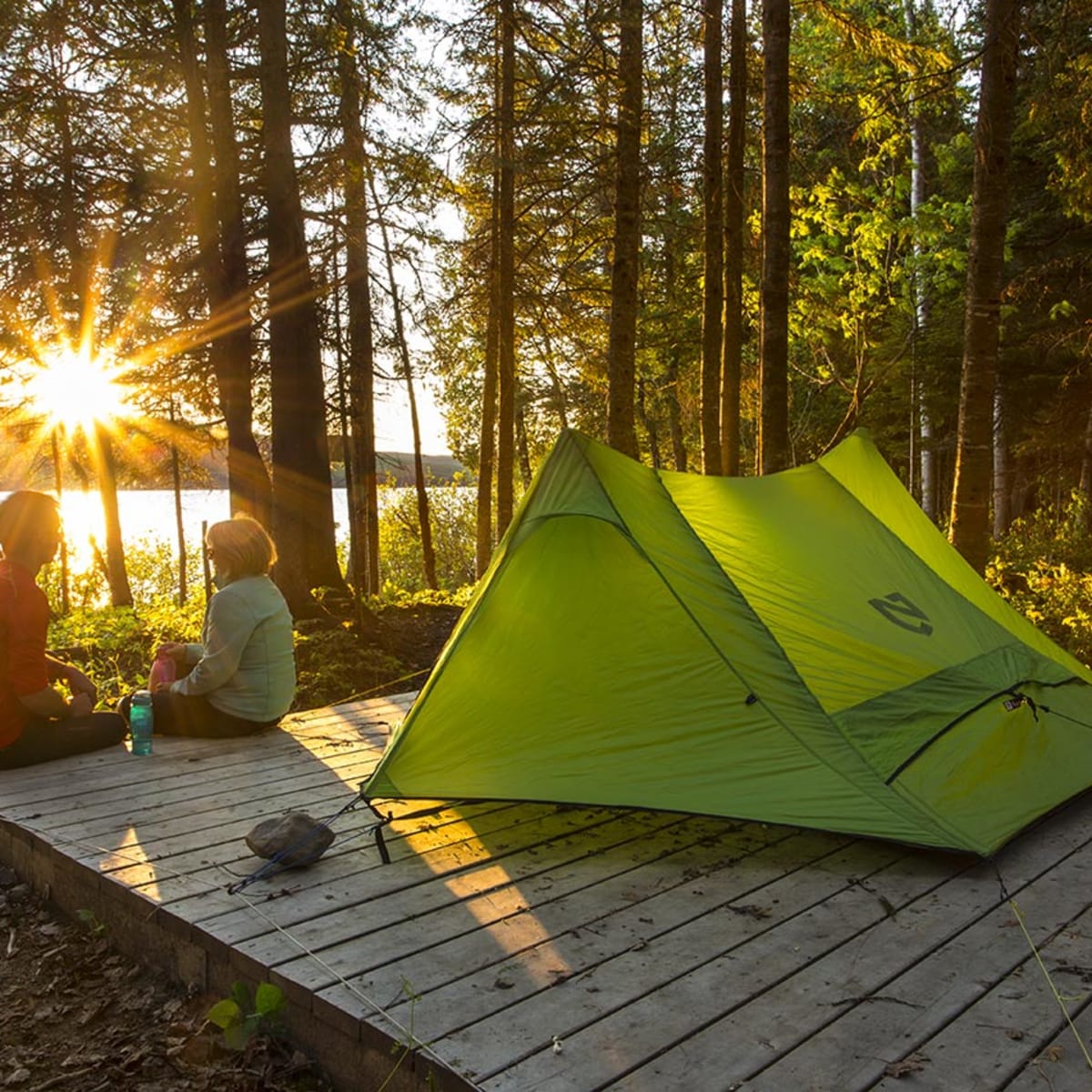 Un couple assis à côté d'une tente verte au Parc national du Lac-Témiscouata.