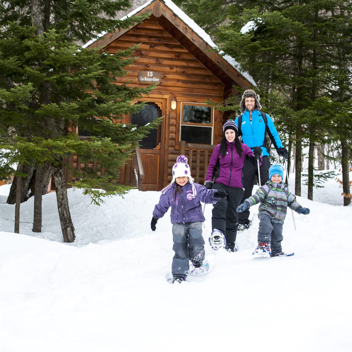 Une famille en raquette devant un chalet au Sommet Morin Heights.