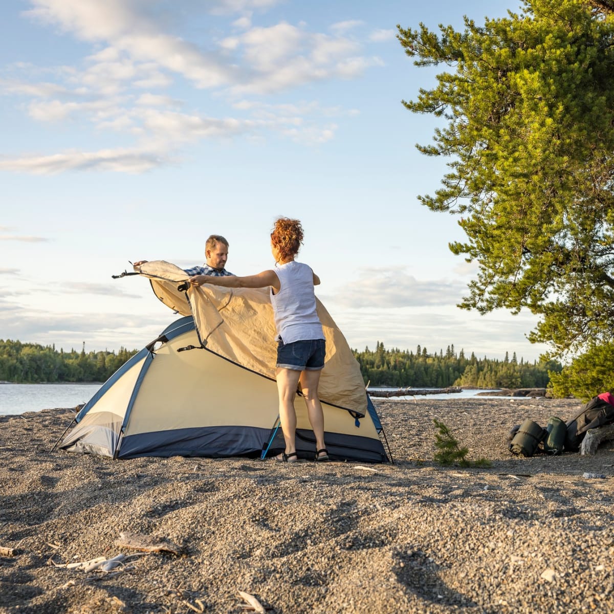 Un couple installe une tente au parc national de la Pointe-Taillon.