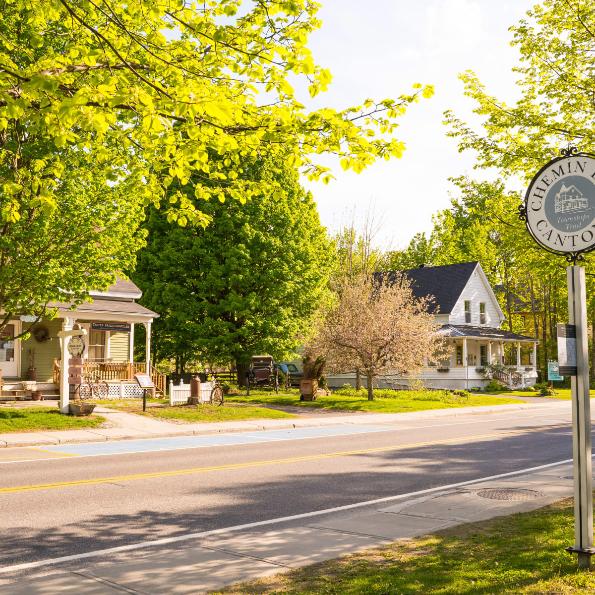 Rue bordée de maison historiques dans le Vieux-Bromont; une pancarte affiche "Chemin des Cantons".