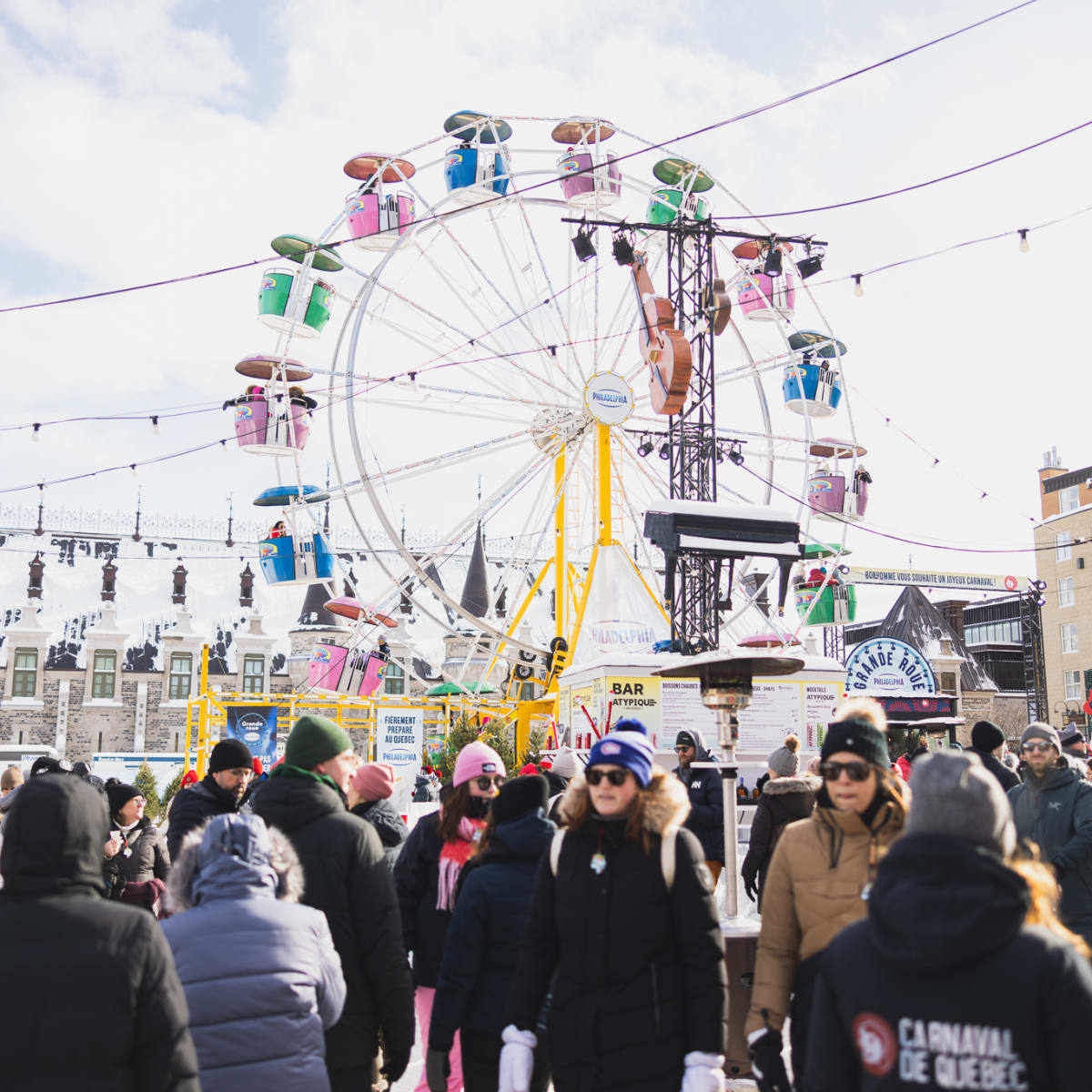 Québec Winter Carnival - A crowd with a Ferris wheel in the background, in winter