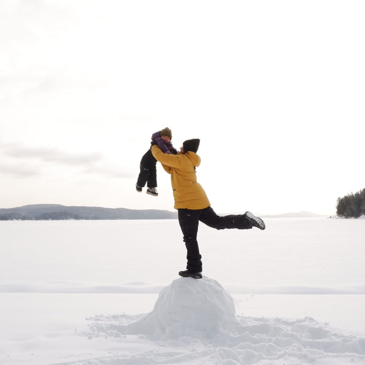 Un parent tient son enfant dans les air au Centre touristique du Lac-Simon, en hiver.