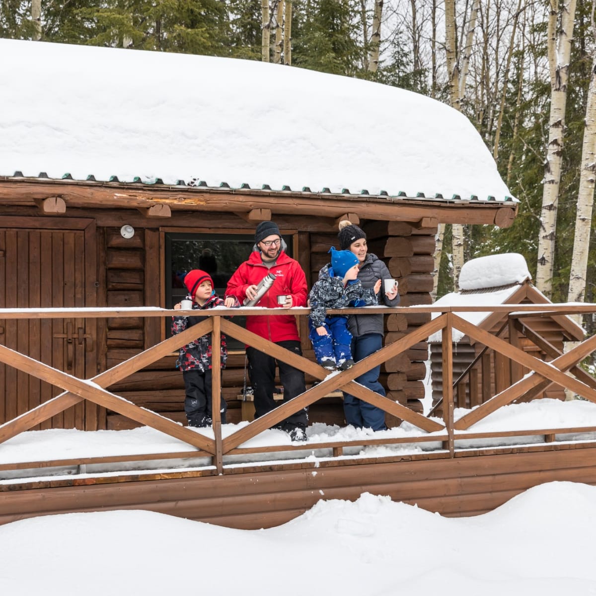 Une famille sur le balcon enneigé d'un chalet du parc national d’Aiguebelle.