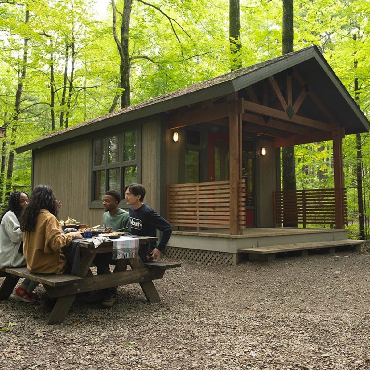 People sitting at a picnic table next to a cabin in Parc national d'Oka.