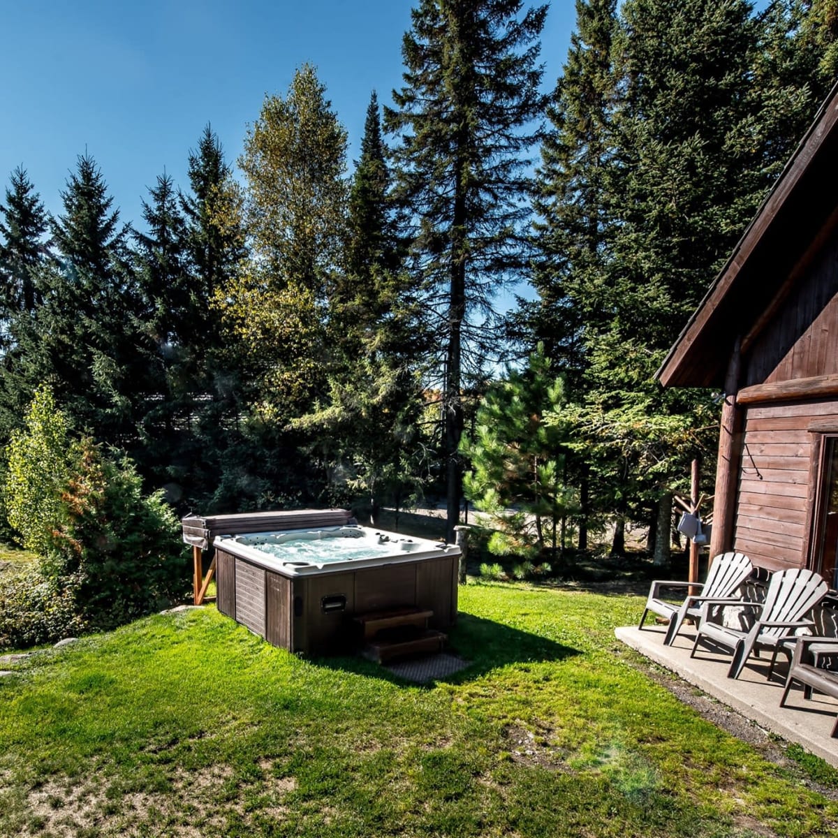 Spa et chaises Adirondack à l'extérieur d'un des Chalets Royal Laurentien.