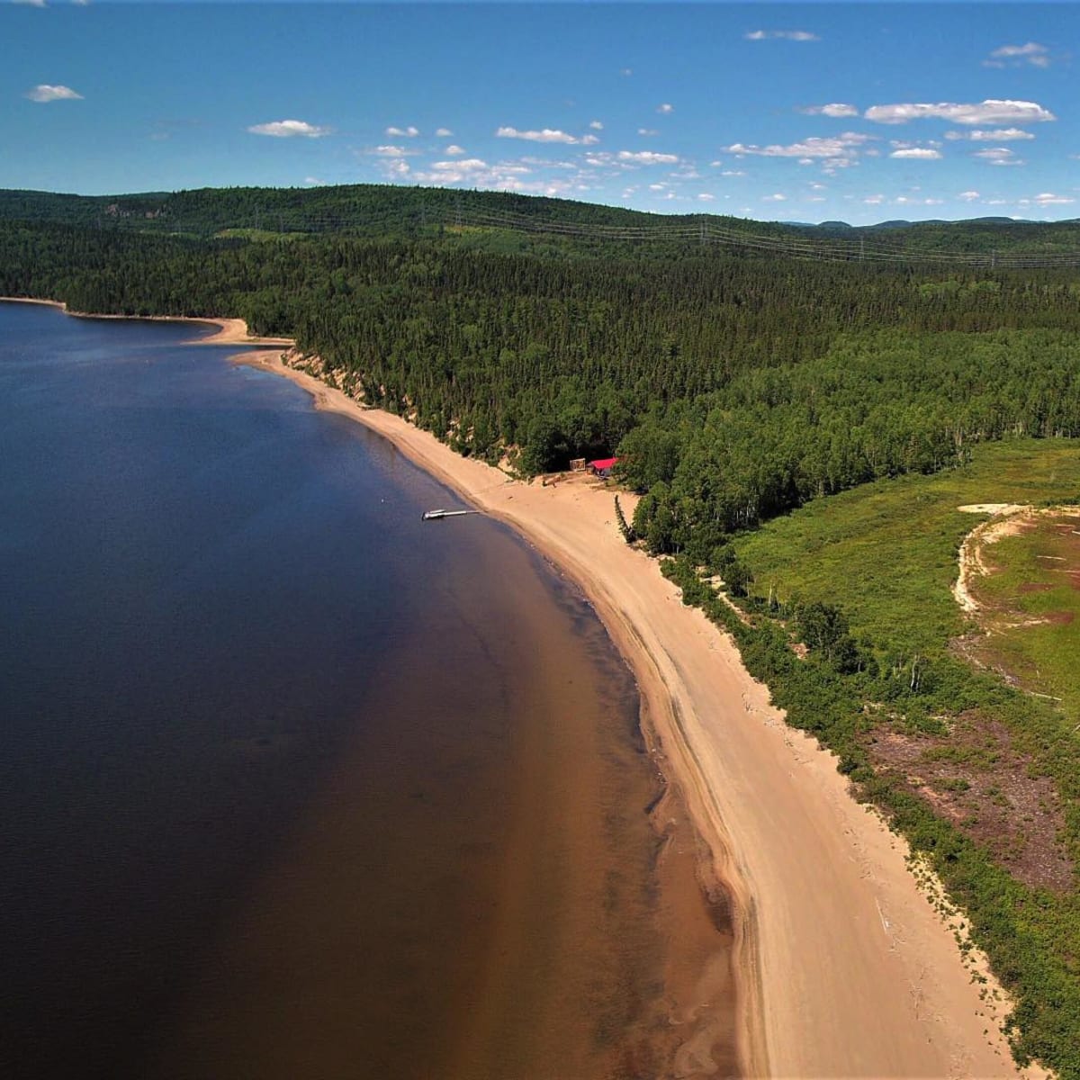 Vue aérienne des paysages naturels de la pourvoirie, avec une plage de sable.