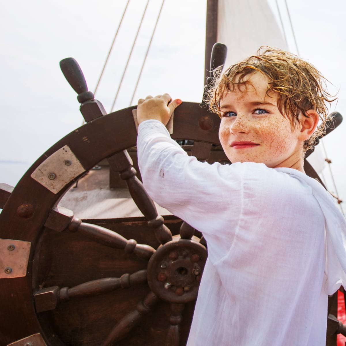 Garçon au gouvernail d'un bateau.