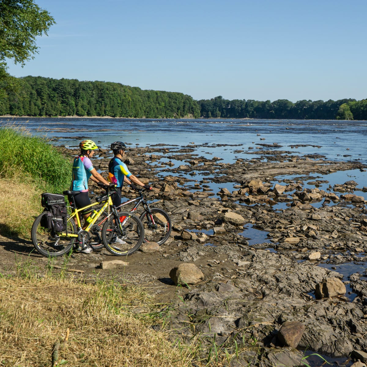 Deux cyclistes arrêtés à proximité d'un plan d'eau rocailleux.