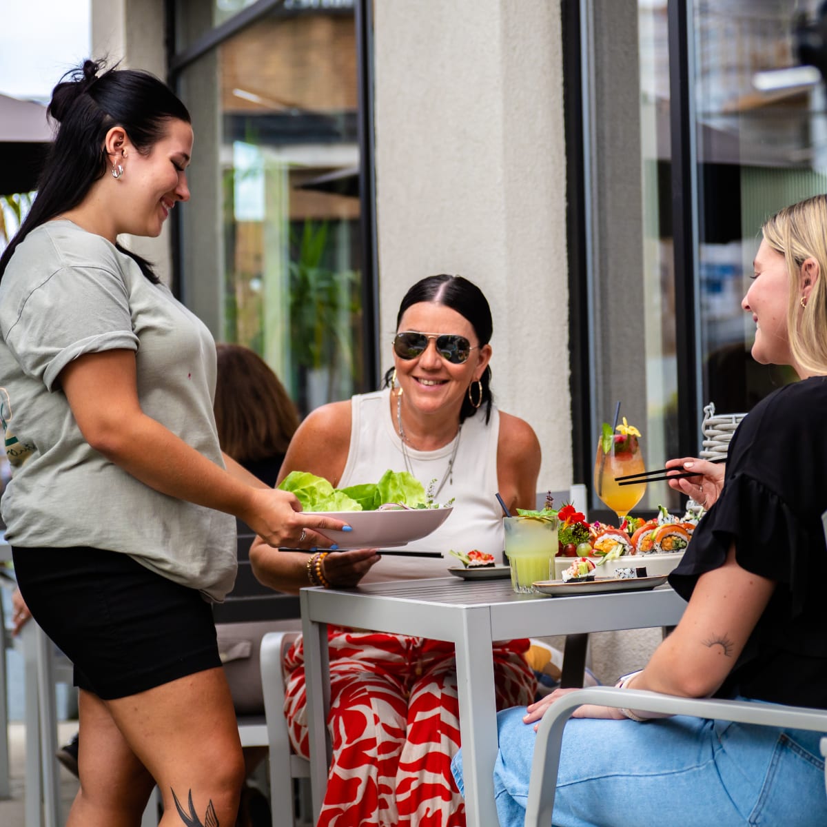 Destination Salaberry-de-Valleyfield - Une serveuse apporte un plat à une table où sont assises deux femmes