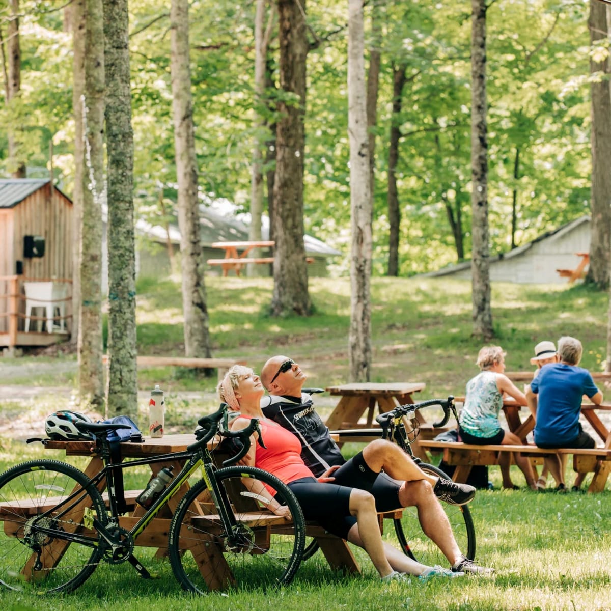 Érablière du Village -  Un homme et une femme sont assis à une table de pique-nique, avec leurs vélos appuyés sur celle-ci.