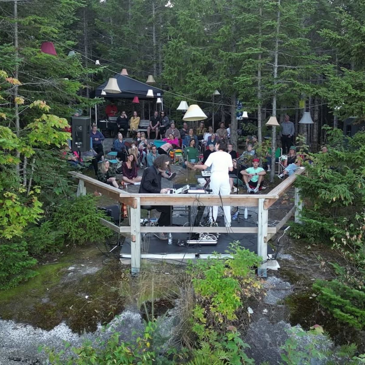 Spectacle en plein air sur une scène en bois, au milieu des arbres