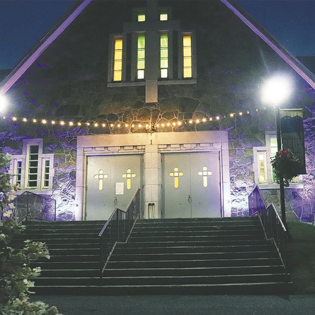 Façade de l'église illuminée en soirée, bannières du festival