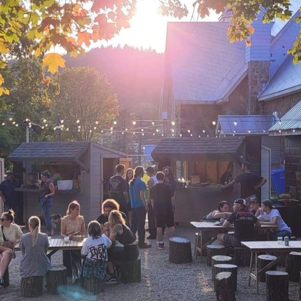Espace festif au soleil couchant — tables, guirlandes et kiosques