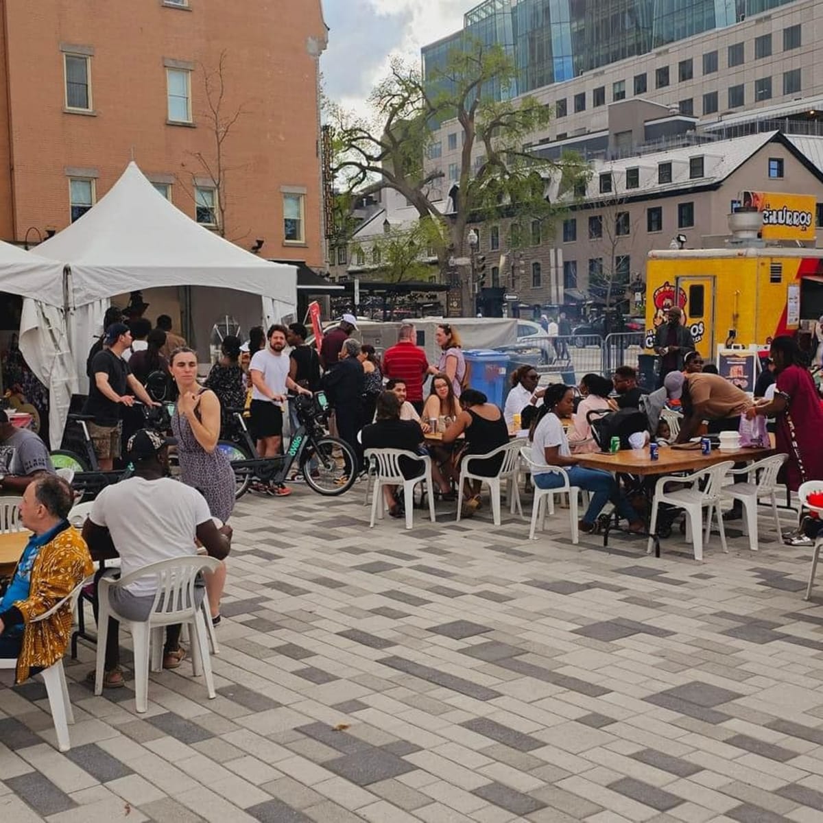 AfriCa Fest - Numerous people sitting at tables, near food trucks and kiosks.