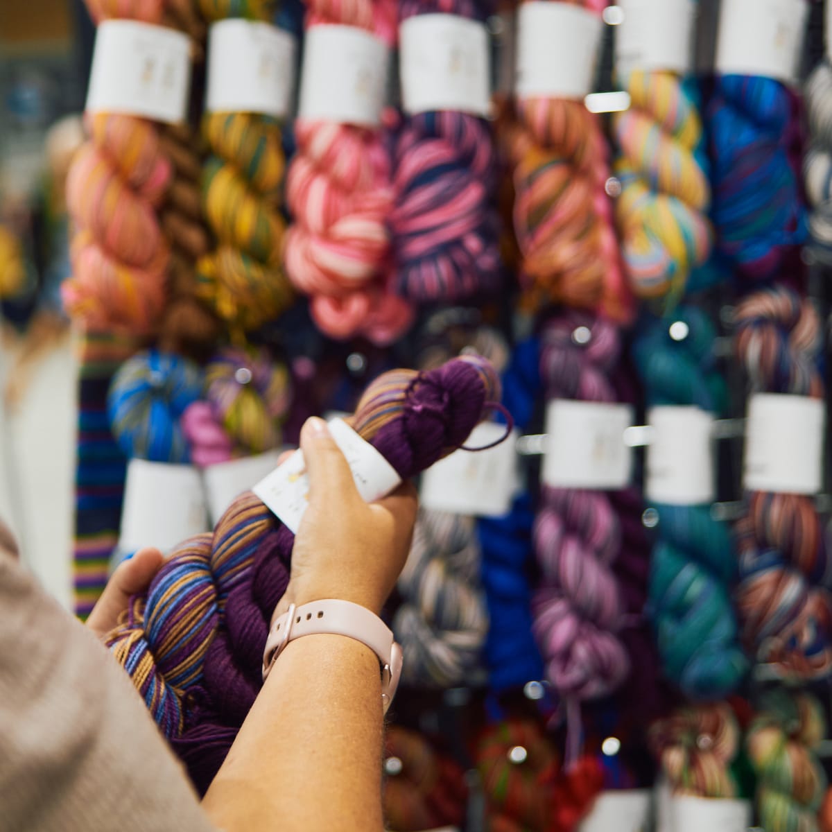 Twist Fibre Festival - A person holds a hank of yarn in front of a display stand.