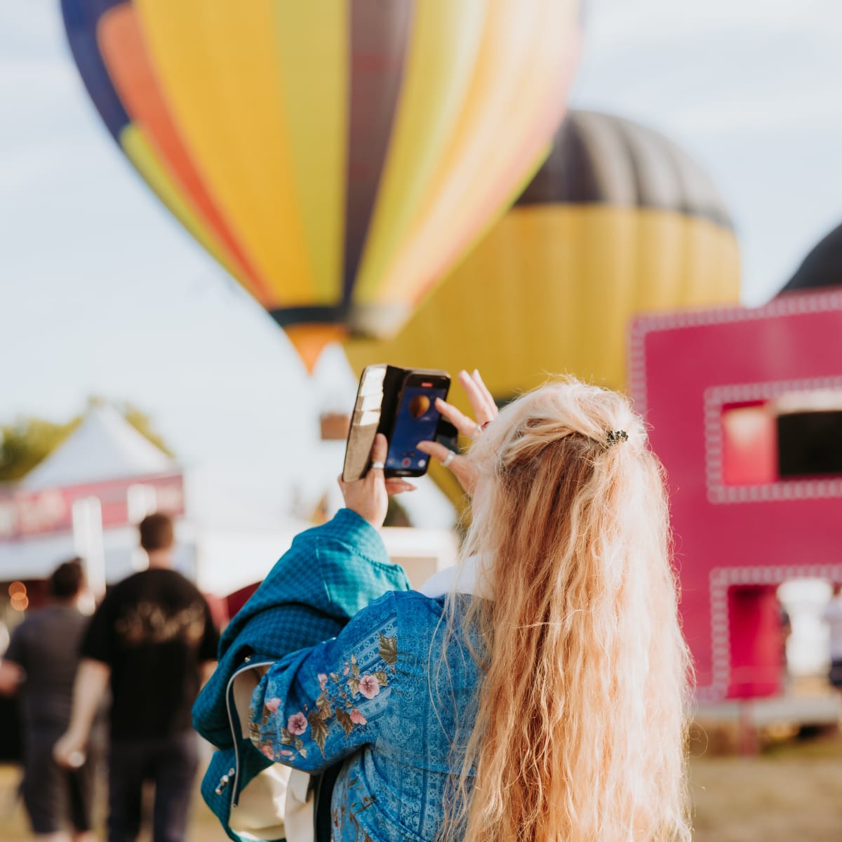Femme prends une photo d'une montgolfière au Festival de montgolfières de Gatineau.