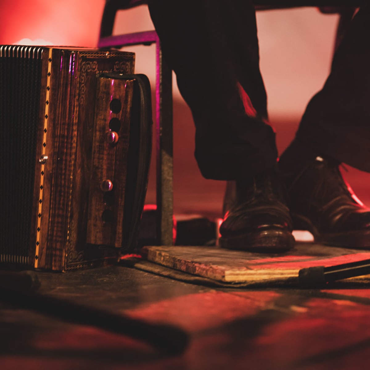 Val-d'Or Traditionnal Music Festival - The feet of a seated person wearing black shoes and standing on a wooden plank, with a microphone in front. An accordion is next to it.