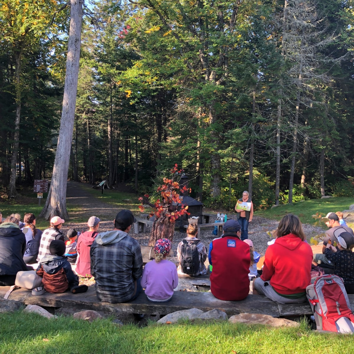 Un groupe est assis et regarde un animateur au Festival des Couleurs du Parc régional Montagne du Diable.