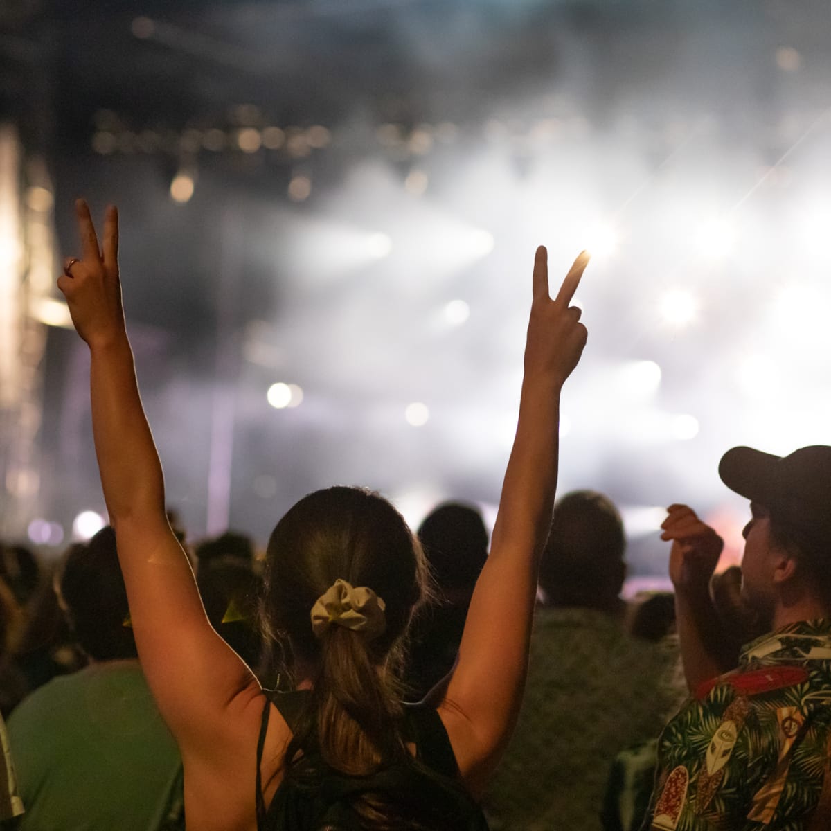 Femme qui lève les bras dans une foule festive en soirée