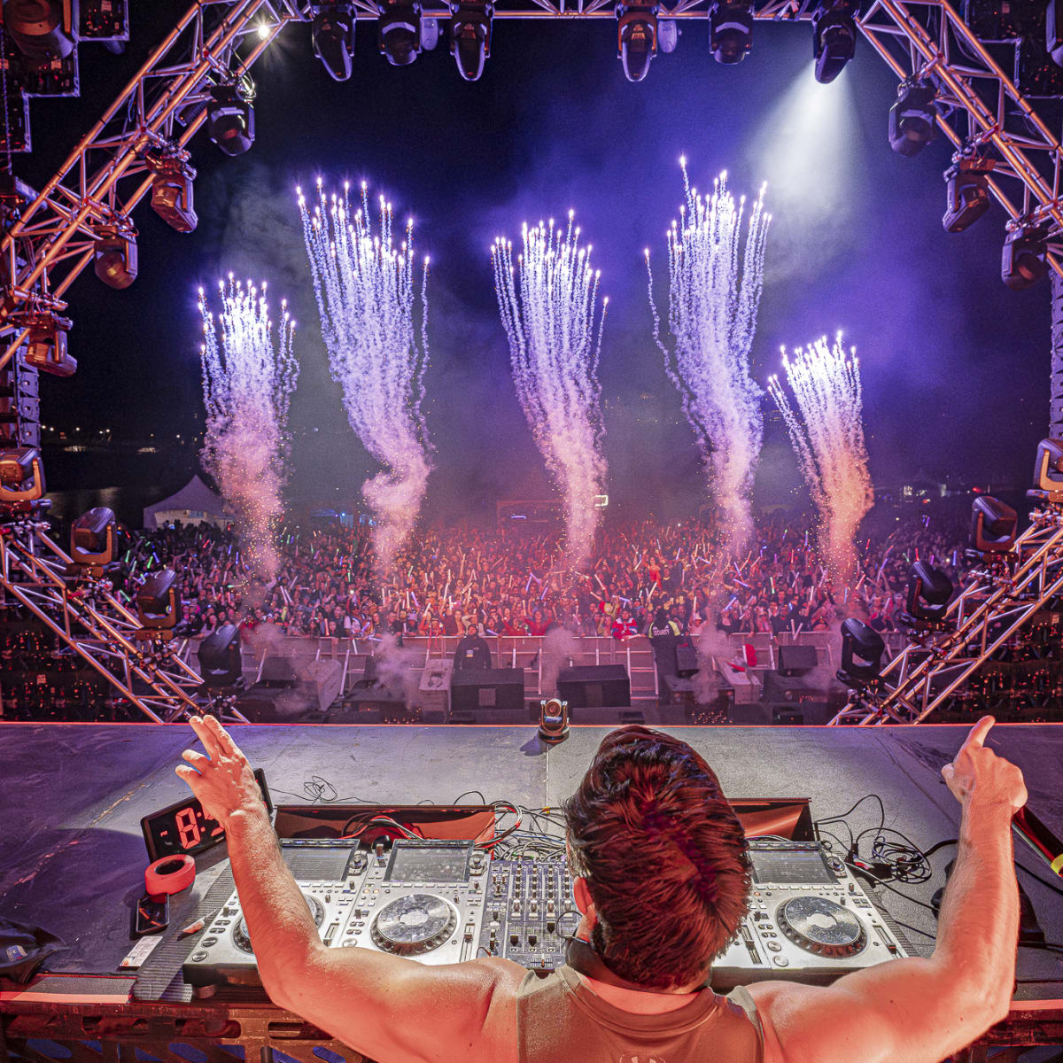 Riverside Festival - DJ on stage in front of a festive crowd, with pyrotechnics.