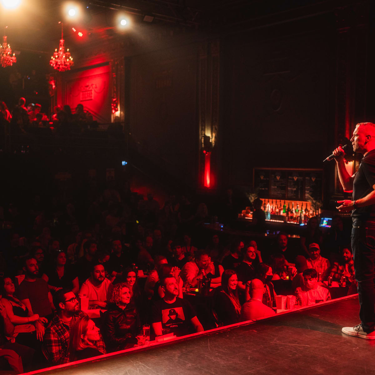 SPASM Festival - On stage, a man is using a microphone, with the audience in the background.