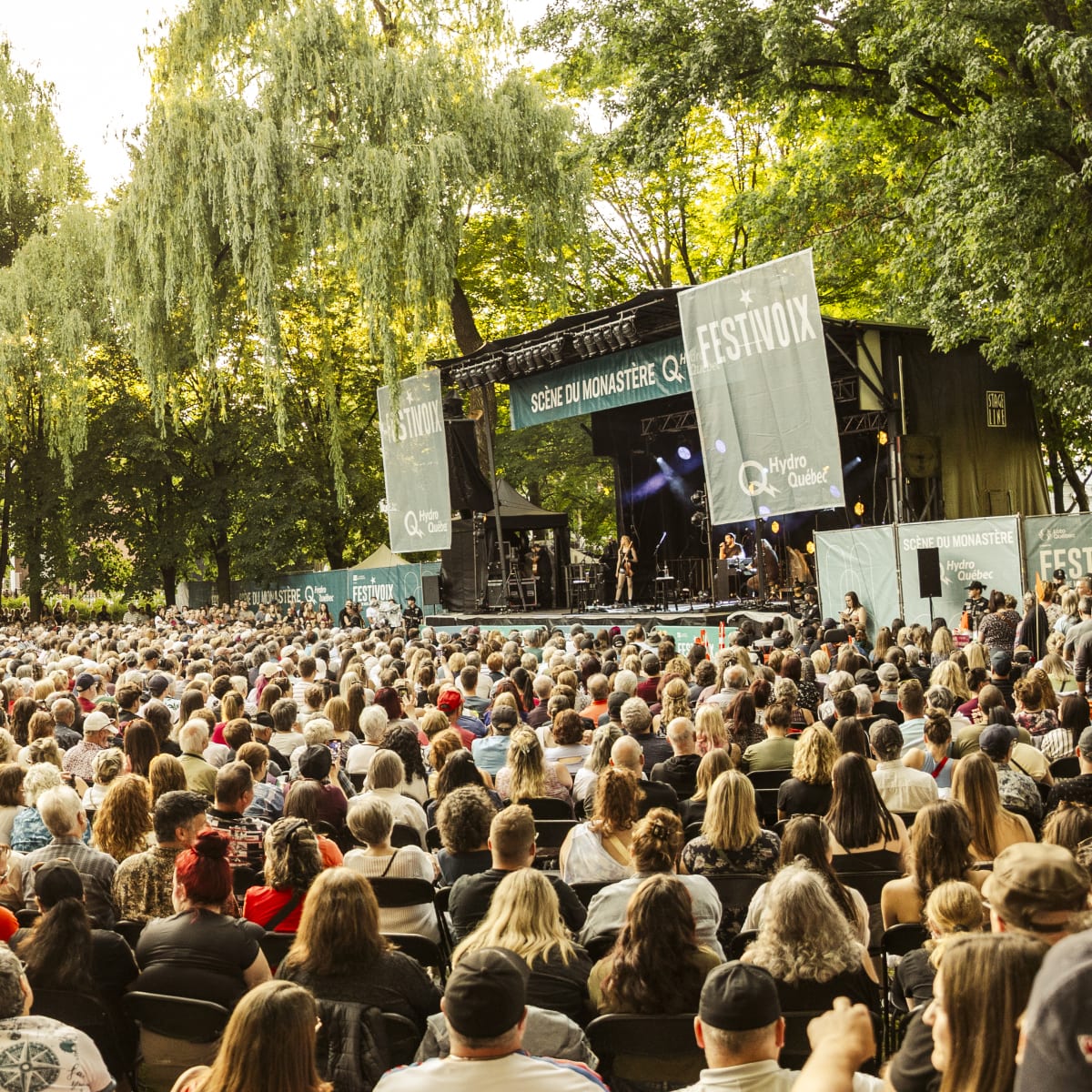Une foule assise devant une scène extérieure du FestiVoix de Trois-Rivières.