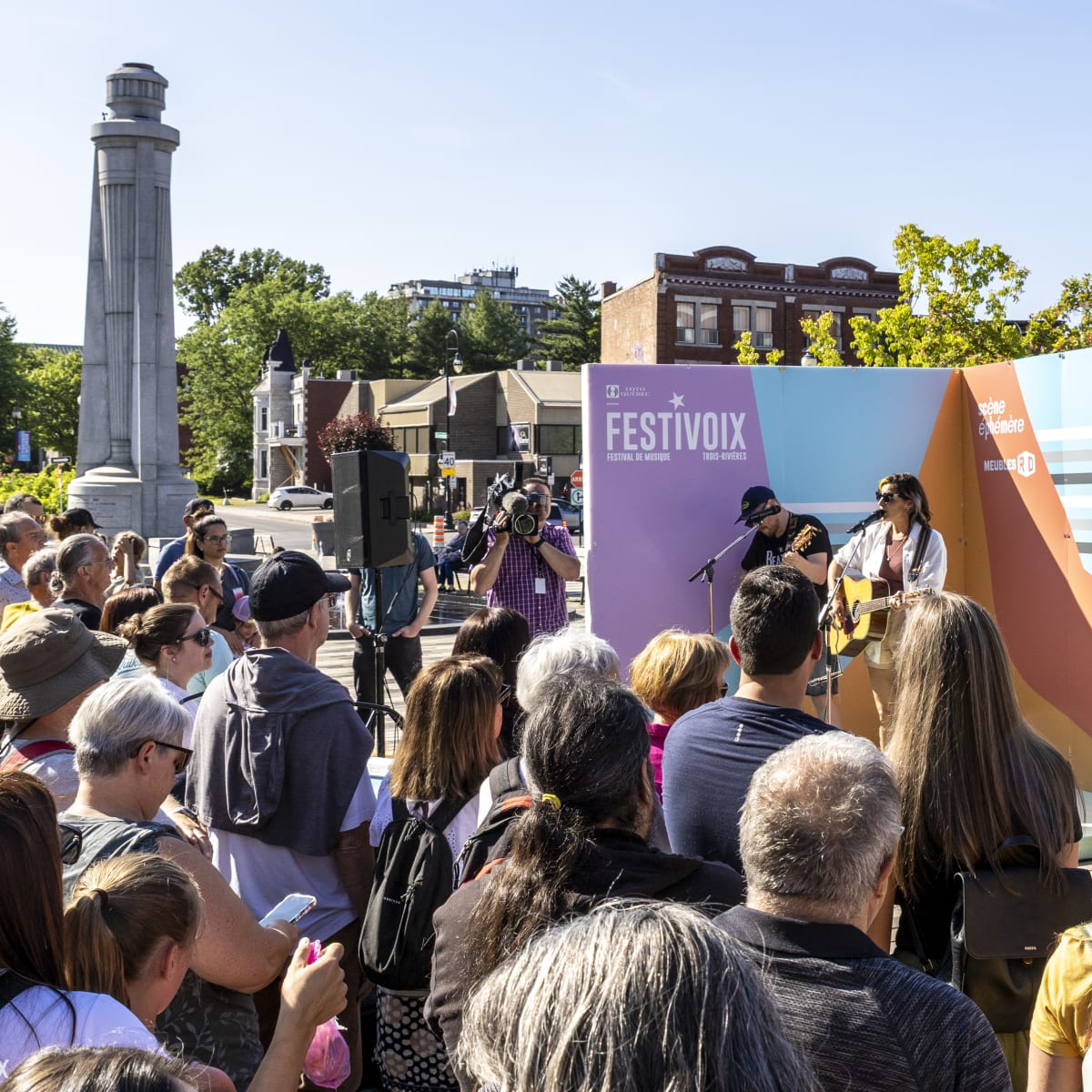 Une foule regarde deux artistes sur une petite scène du FestiVoix de Trois-Rivières.