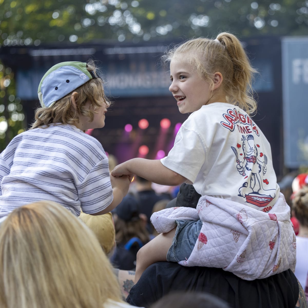 Deux enfants assis sur les épaules d'adultes au FestiVoix de Trois-Rivières.