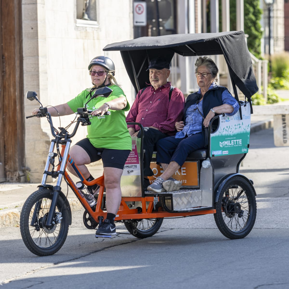 Deux adultes se font transportés en vélo-taxi au FestiVoix de Trois-Rivières.