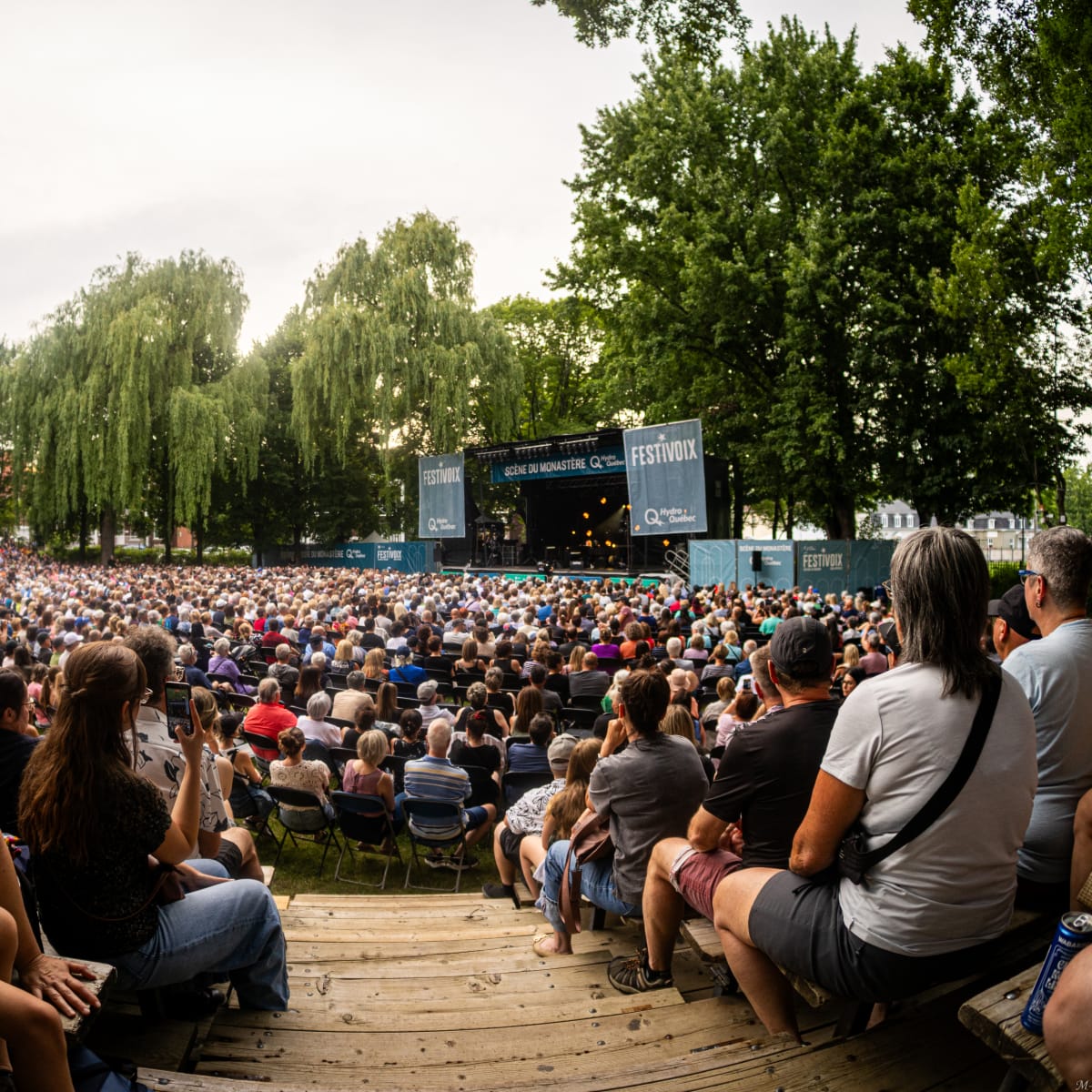 Une foule assise regarde une scène extérieure au FestiVoix de Trois-Rivières.