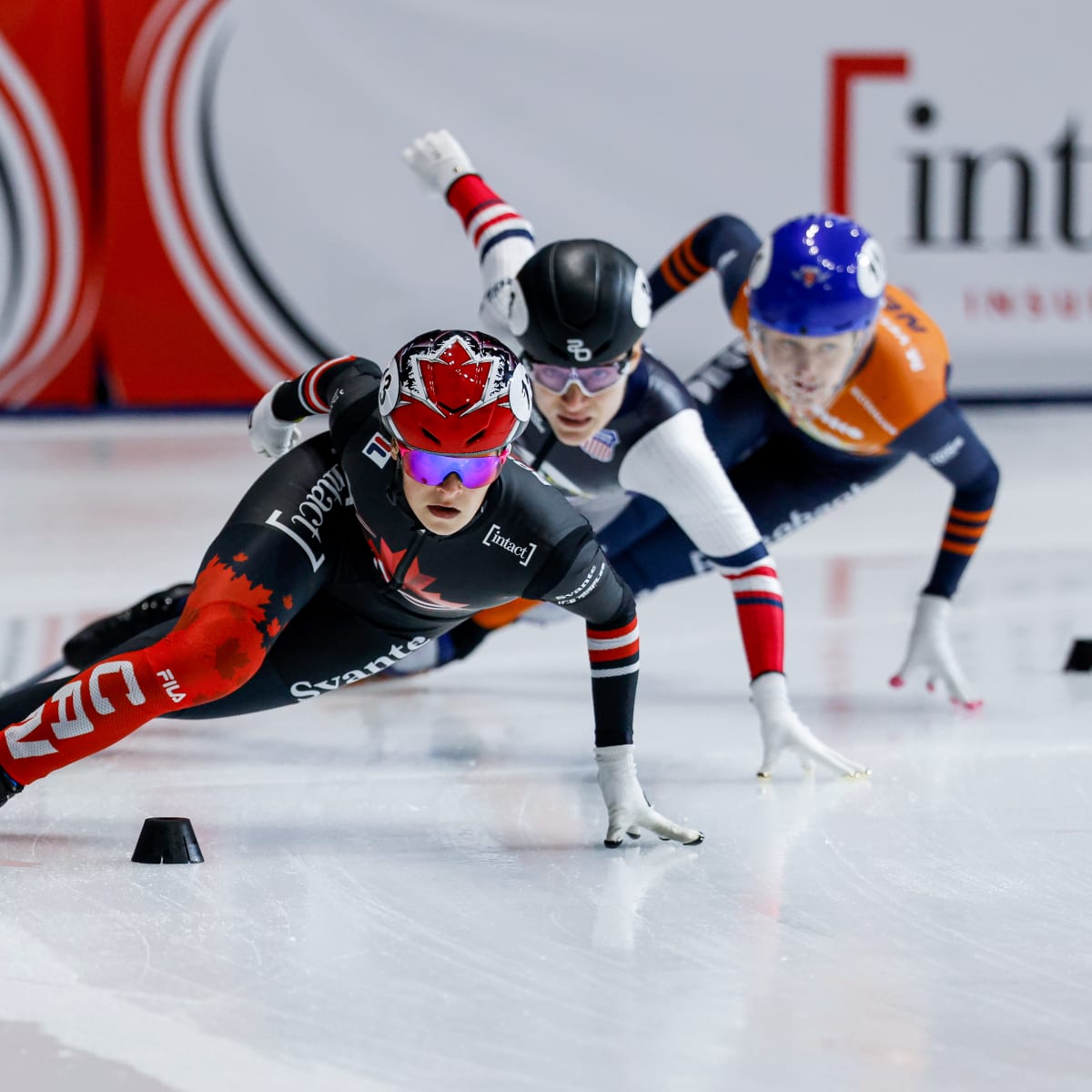Trois patineuses de vitesse lors d'un virage.