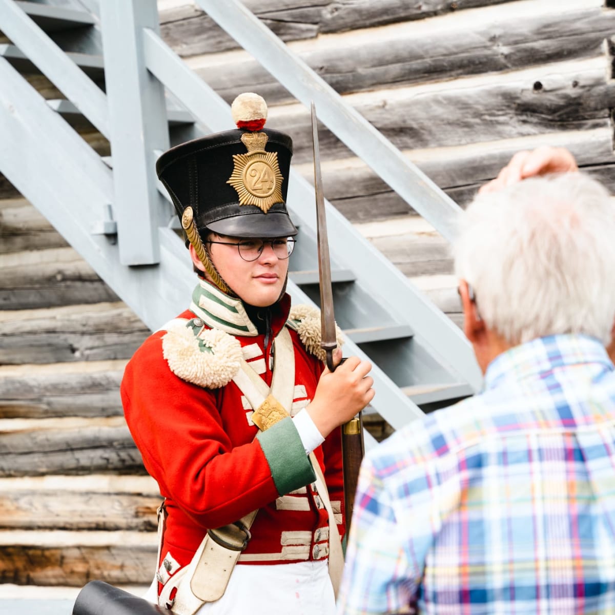 Soldat en uniforme rouge se tenant devant un homme âgé.
