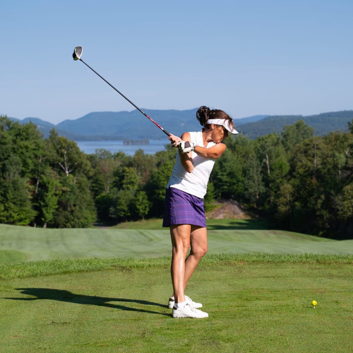 Une femme prend son élan sur un terrain de golf des Laurentides en été.