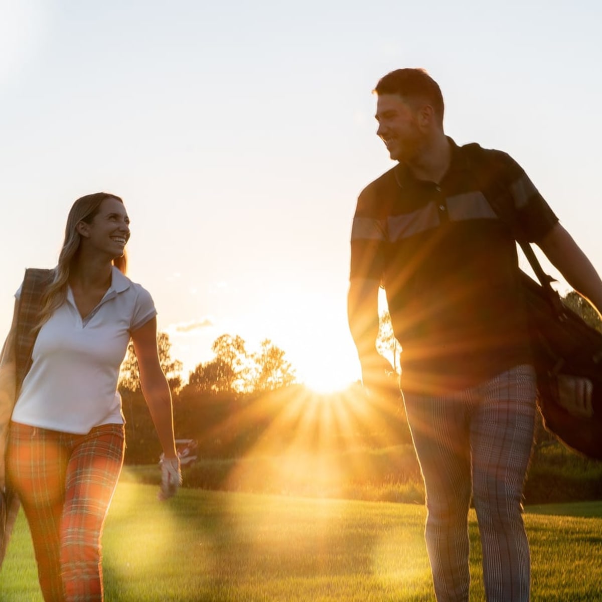 Deux joueurs de golf marchant ensemble sur un terrain des Laurentides au coucher du soleil.