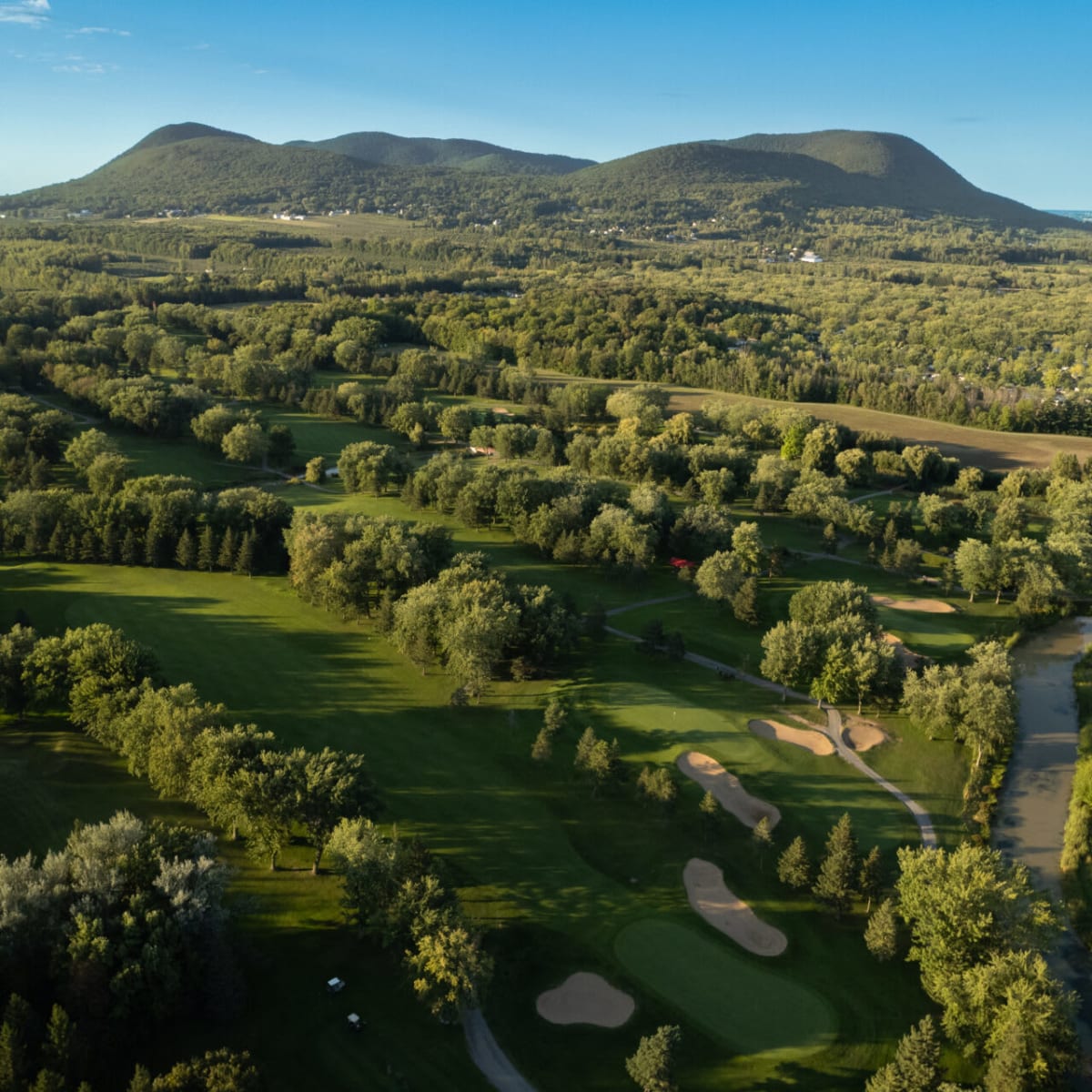 Vue aérienne du Golf de Rouville avec une montagne en arrière-plan. 