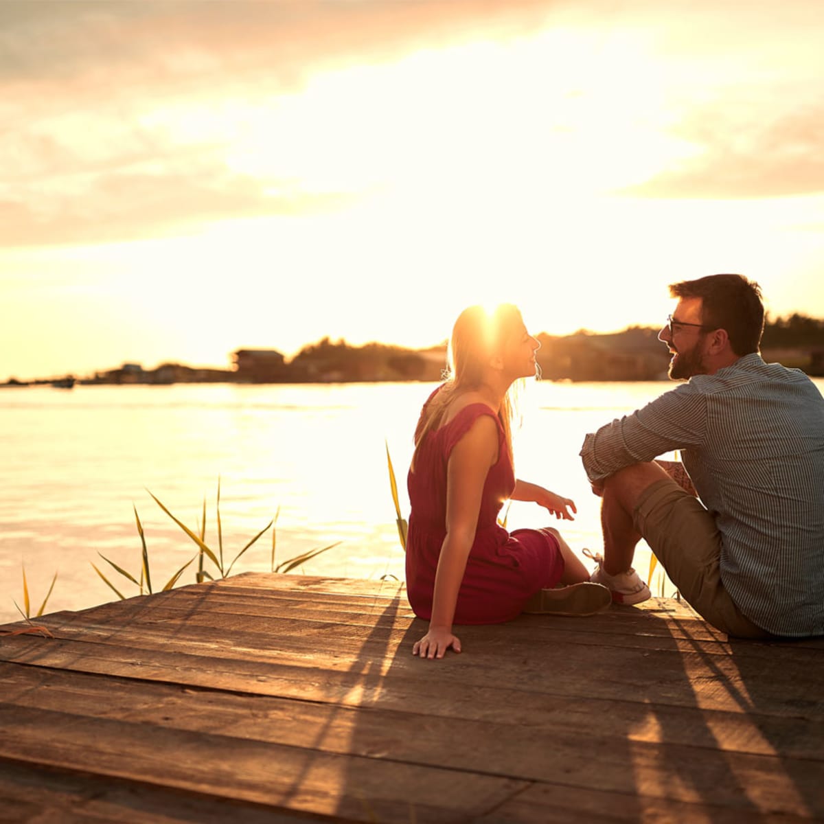 Couple sitting on a dock at sunset