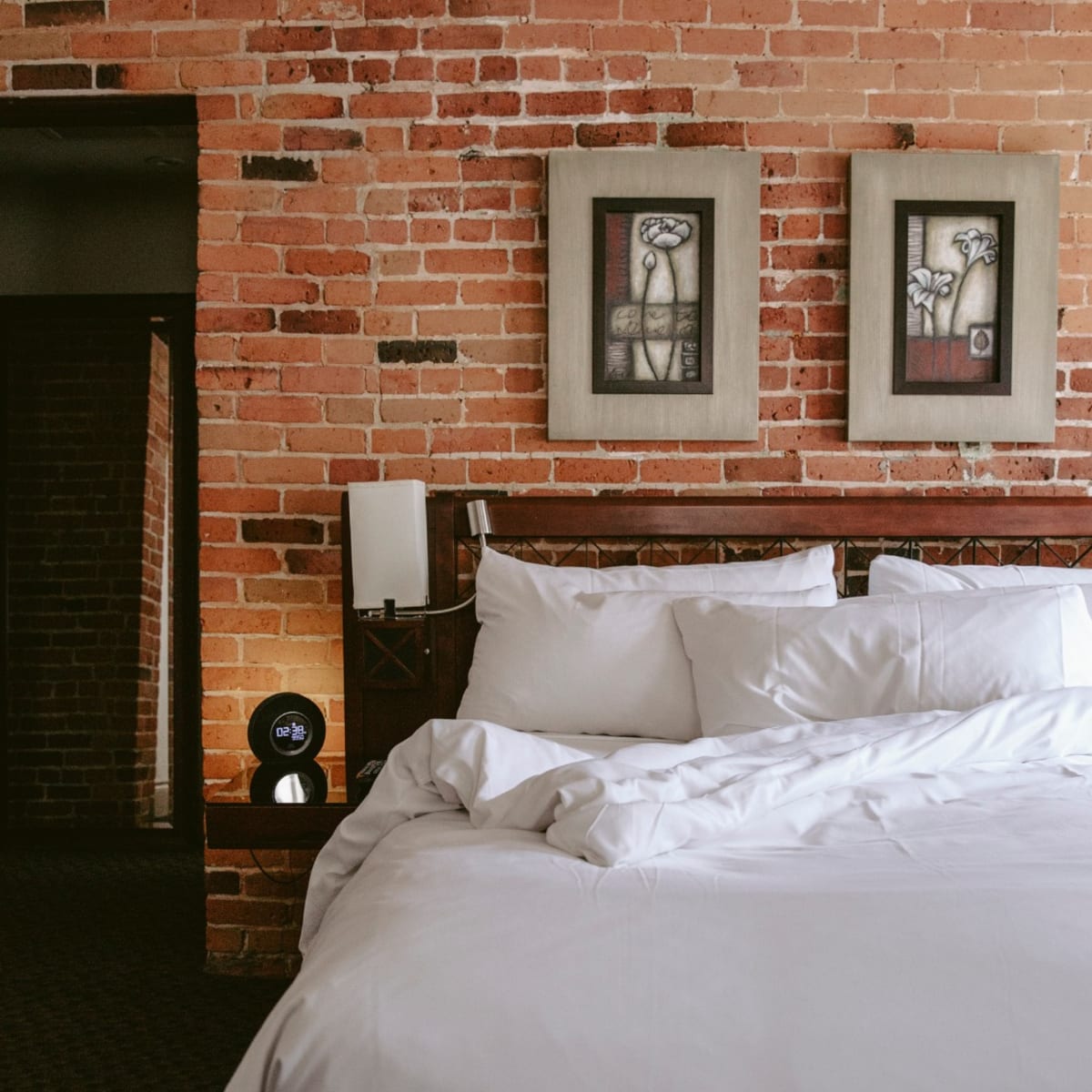 Hôtel Nelligan - Un lit avec des draps blancs et un mur de briques