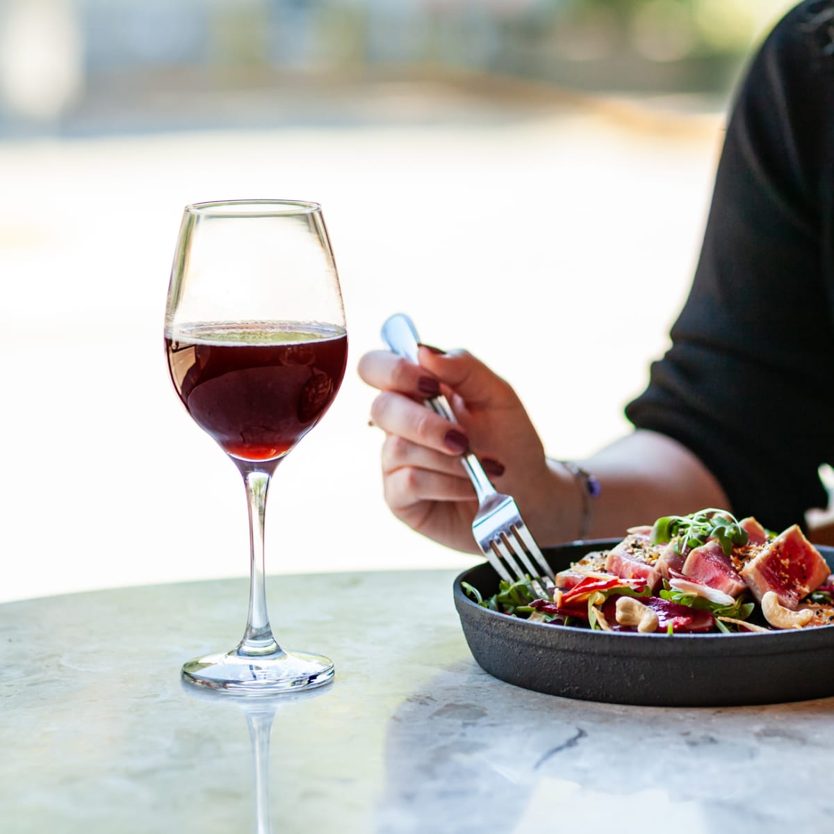 Femme dégustant du vin rouge et un plat à l'hôtel.