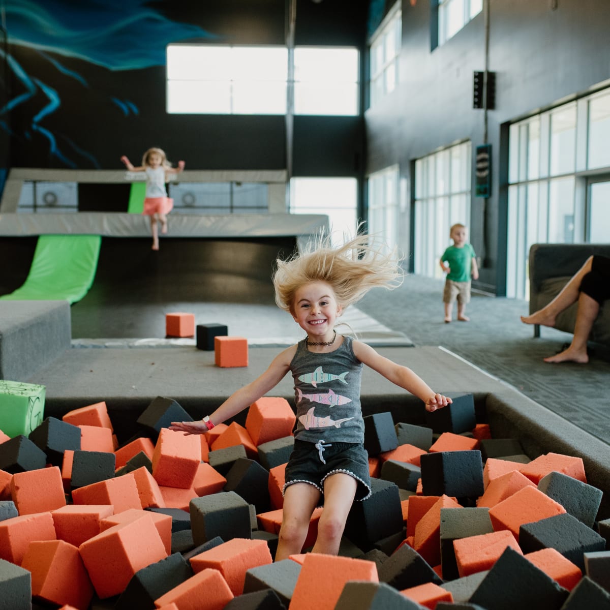 Une fille saute dans un bassin de blocs de mousse à iSaute.