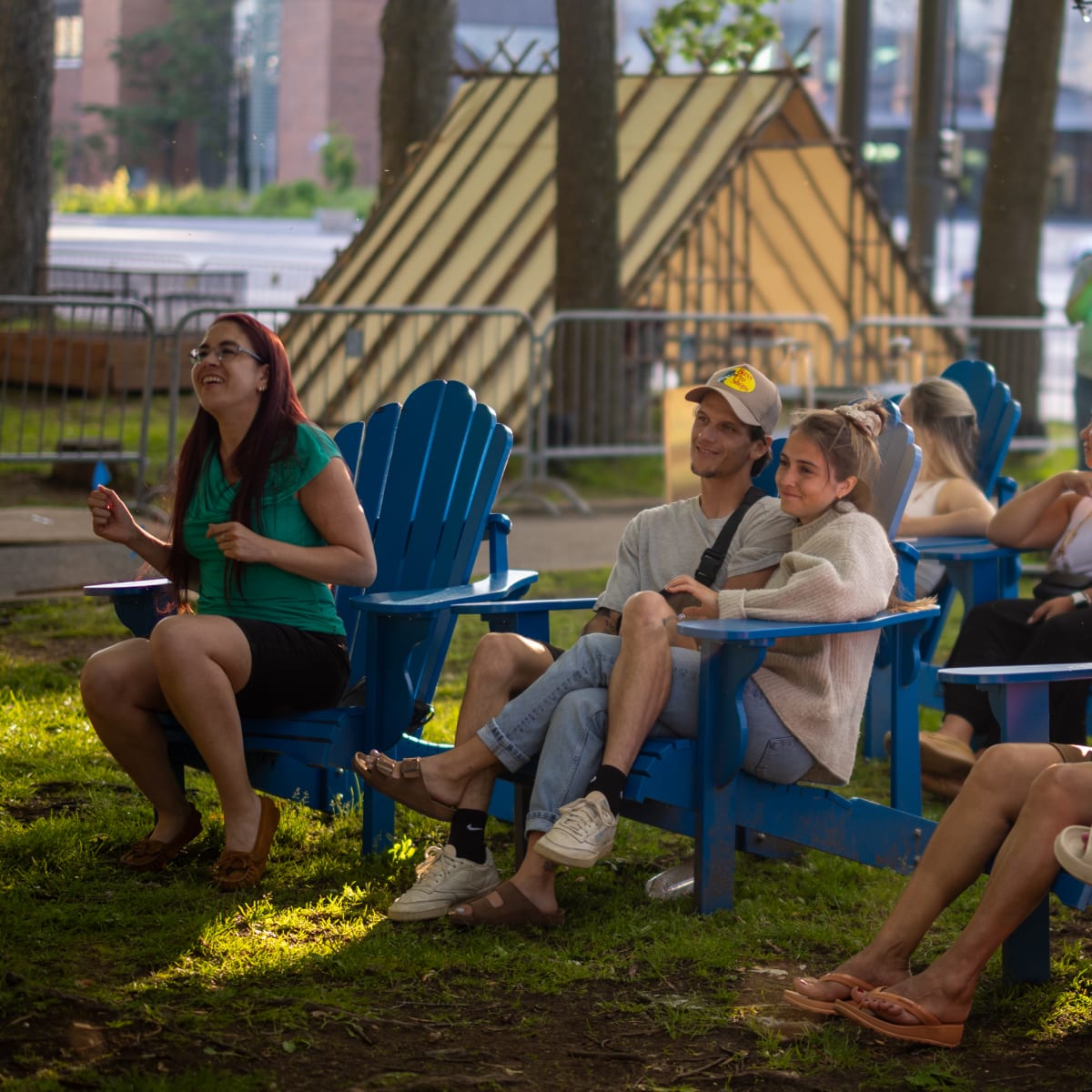 Personnes assises sur des chaises d'extérieur devant un spectacle.