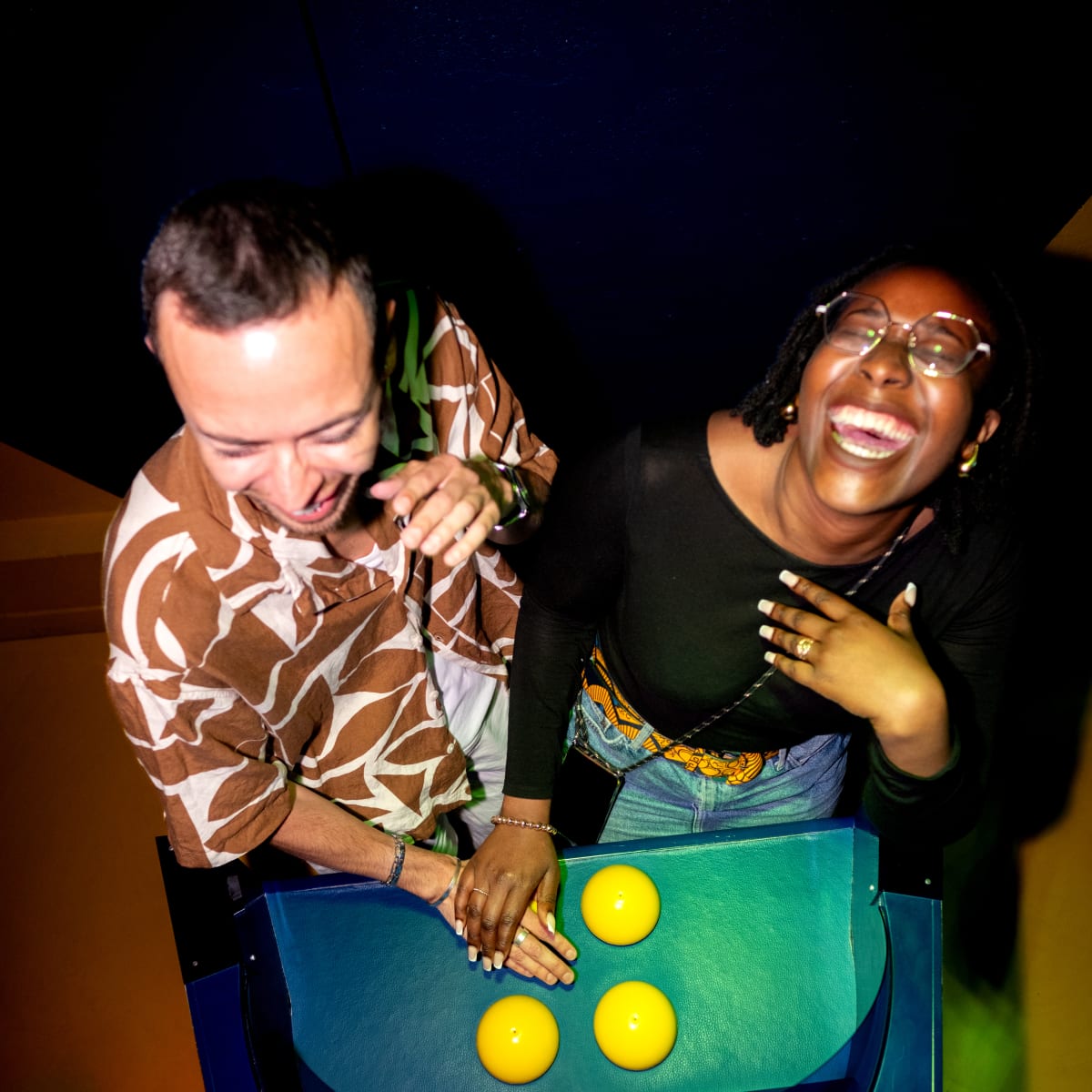 La Boîte à Questions – Quiz Room Montréal - Deux personnes joyeusement penchées au-dessus d'une machine interactive