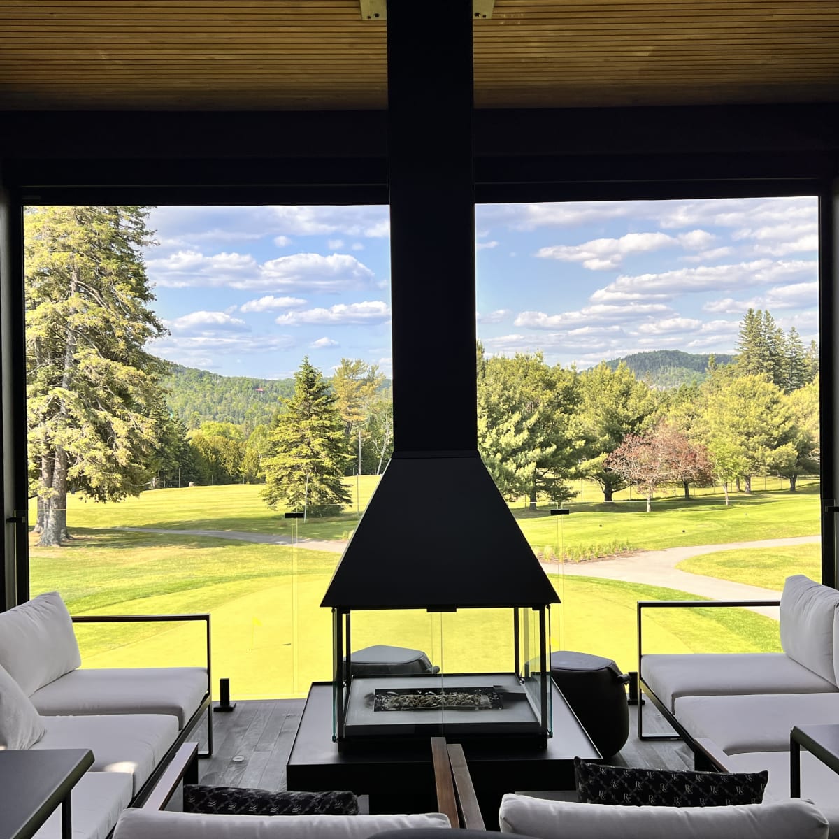 Le Val-Mo Pub Gourmand - Terrasse avec sofas et foyer, avec une vue sur le golf