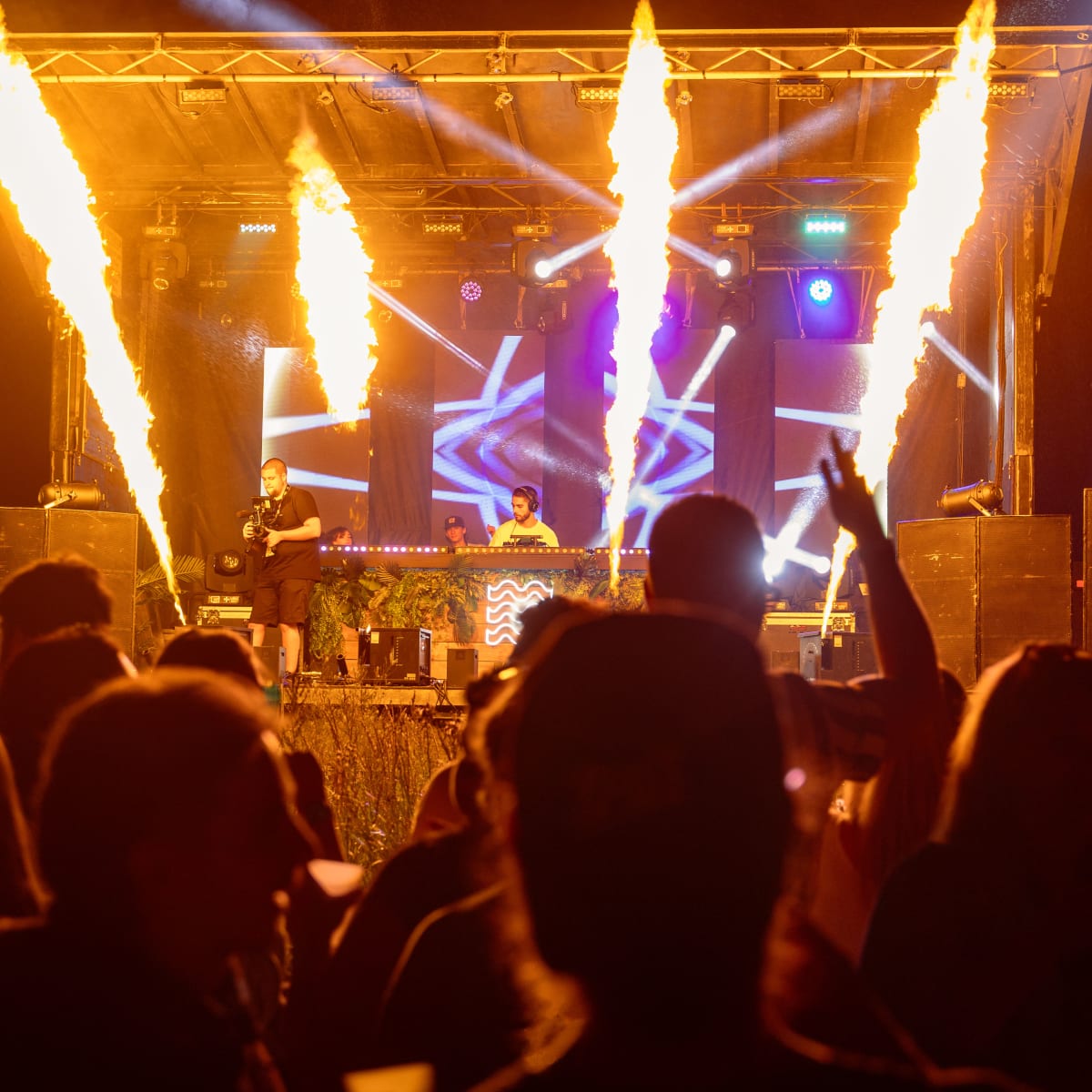 M DGTL - A DJ is on stage during the night, illuminated by flame projectors.
