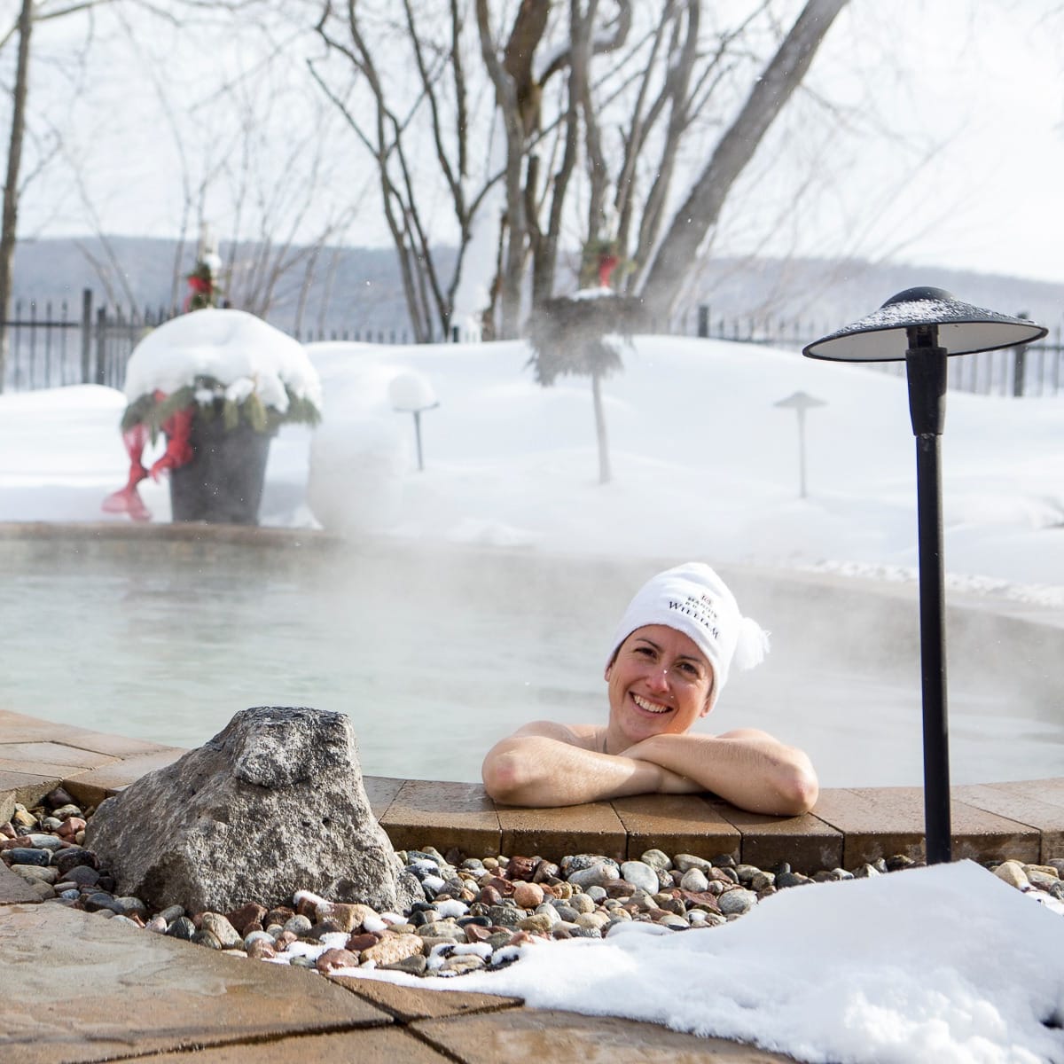 Femme dans le spa extérieure du Manoir du lac William en hiver.