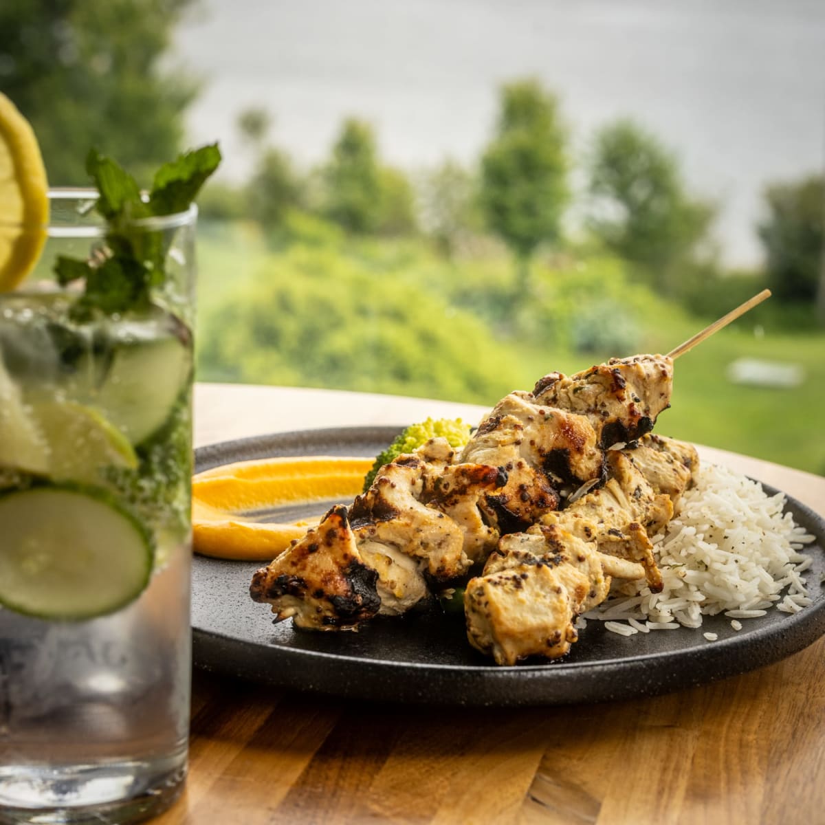 A plate of breaded skewers served with a cocktail featuring citrus slices.